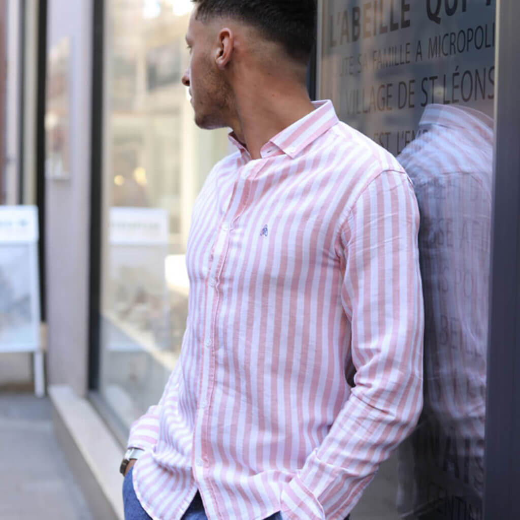homme regardant derrière lui avec chemise sable rose abeyron appuyé devant la boutique de rodez